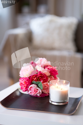 Image of burning fragrance candle and flower bunch at home