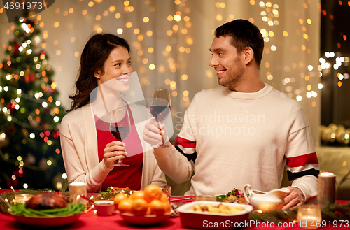 Image of happy couple drinking red wine at christmas dinner