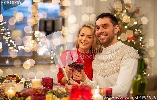 Image of couple taking picture by selfie stick at christmas