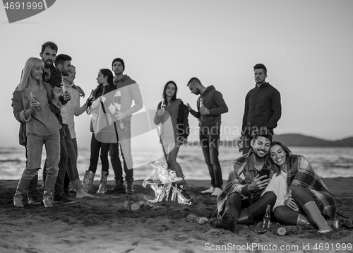 Image of Couple enjoying bonfire with friends on beach