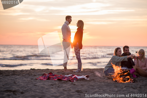 Image of Couple enjoying with friends at sunset on the beach