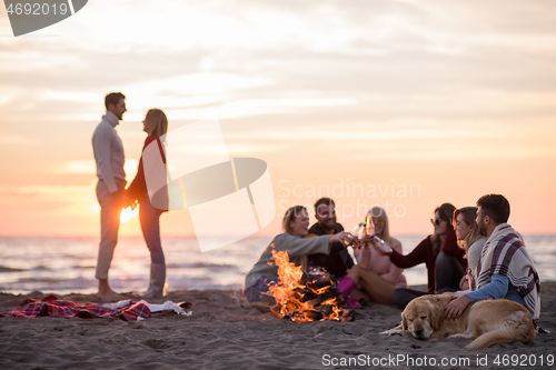 Image of Couple enjoying with friends at sunset on the beach