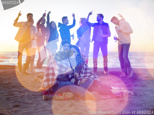 Image of Couple enjoying with friends at sunset on the beach