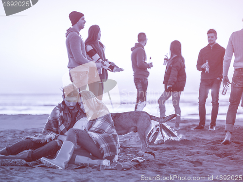 Image of Couple enjoying with friends at sunset on the beach