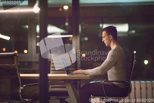 Image of man working on laptop in dark office