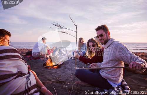 Image of Couple enjoying with friends at sunset on the beach