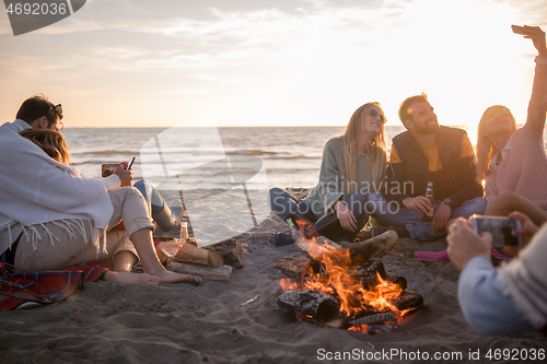 Image of Friends having fun at beach on autumn day