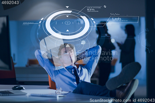 Image of businessman sitting with legs on desk at office