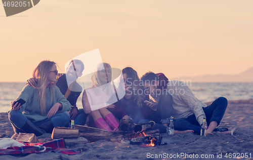 Image of Friends having fun at beach on autumn day