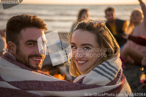 Image of Couple enjoying with friends at sunset on the beach