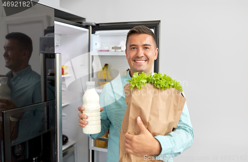 Image of man with new purchased food at home fridge