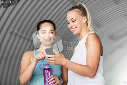 Image of women or female friends with smartphone and flask