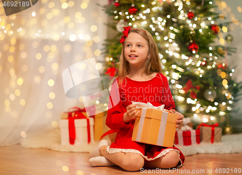 Image of smiling girl with christmas gift at home