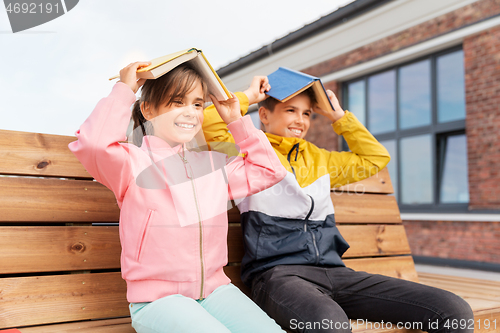 Image of school children with books having fun outdoors