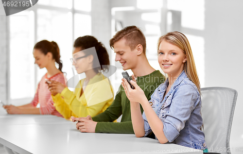 Image of happy high school students with smartphones