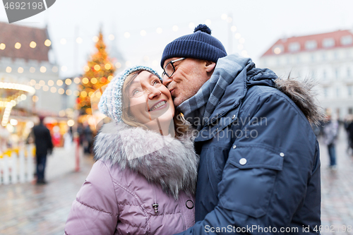 Image of happy senior couple kissing at christmas market