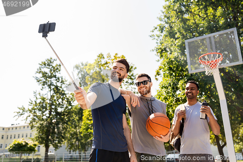 Image of happy men taking selfie at basketball playground