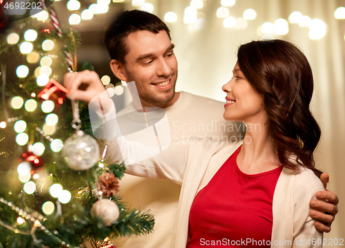 Image of happy couple decorating christmas tree at home