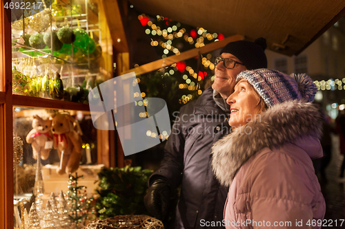 Image of happy senior couple hugging at christmas market