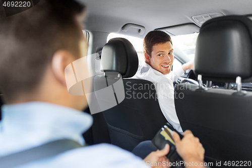 Image of male car driver looking at passenger with wallet