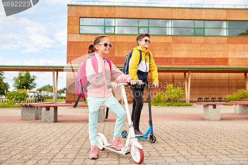 Image of happy school children with backpacks and scooters