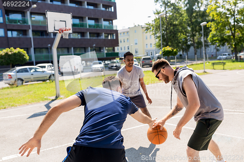 Image of group of male friends playing street basketball