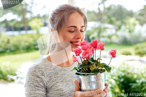 Image of young woman with cyclamen flowers at summer garden