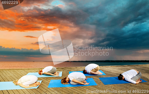 Image of group of people making yoga exercises outdoors