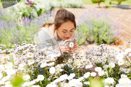 Image of happy woman smelling chamomile flowers in garden