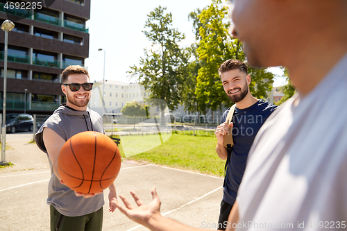 Image of group of male friends playing street basketball