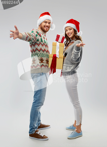 Image of happy couple in christmas sweaters with gifts