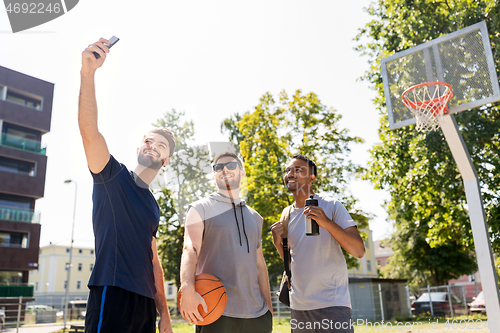 Image of happy men taking selfie at basketball playground