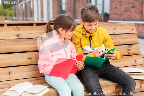 Image of school children with notebooks sitting on bench