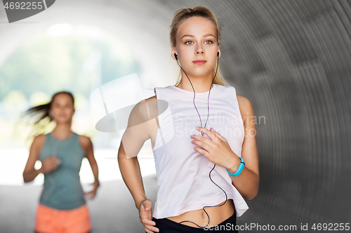 Image of women or female friends with earphones running