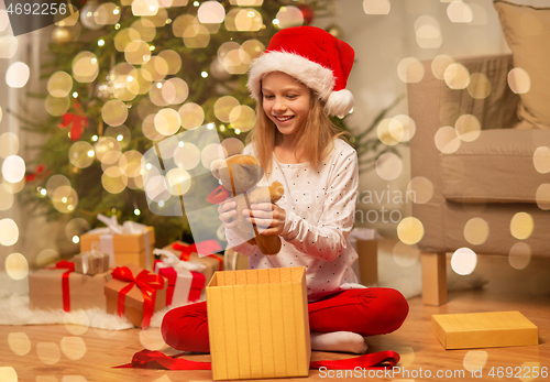 Image of smiling girl in santa hat with christmas gift