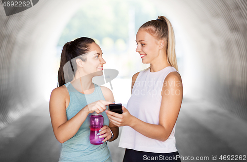 Image of women or female friends with smartphone and flask