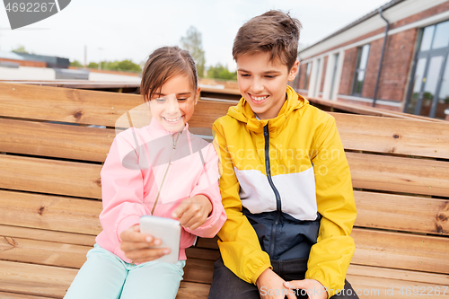 Image of children with smartphones sitting on street bench