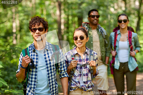 Image of group of friends with backpacks hiking in forest