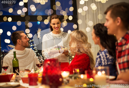 Image of happy friends having christmas dinner at home