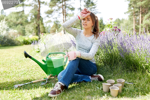 Image of tired young woman with garden tools in summer