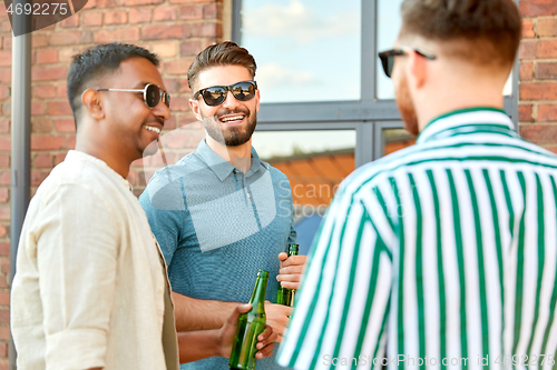 Image of happy male friends drinking beer in summer city