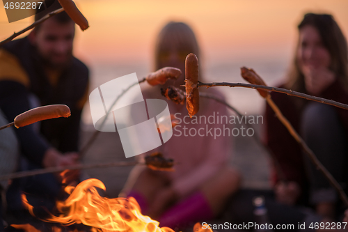 Image of Group Of Young Friends Sitting By The Fire at beach