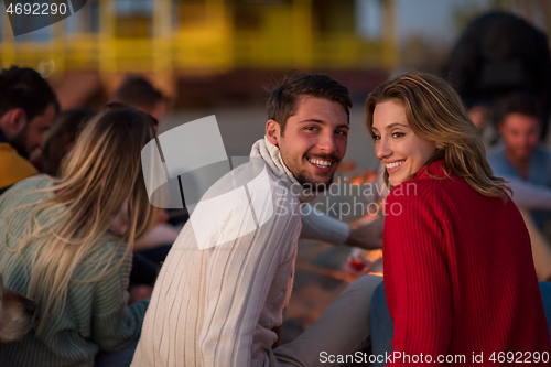 Image of Couple enjoying with friends at sunset on the beach