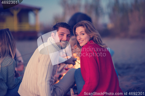 Image of Couple enjoying with friends at sunset on the beach