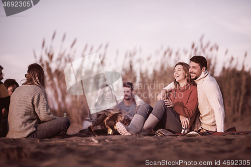 Image of Couple enjoying with friends at sunset on the beach