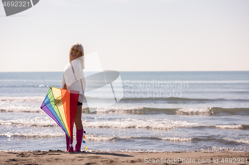 Image of Young Woman with kite at beach on autumn day