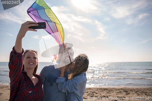 Image of Group of friends making selfie on beach during autumn day