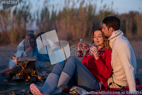 Image of Couple enjoying with friends at sunset on the beach