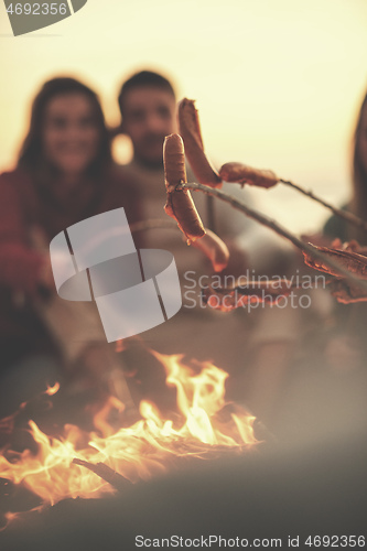 Image of Group Of Young Friends Sitting By The Fire at beach