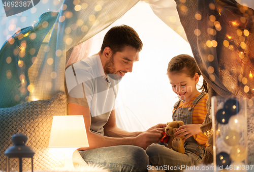 Image of happy family playing with toy in kids tent at home